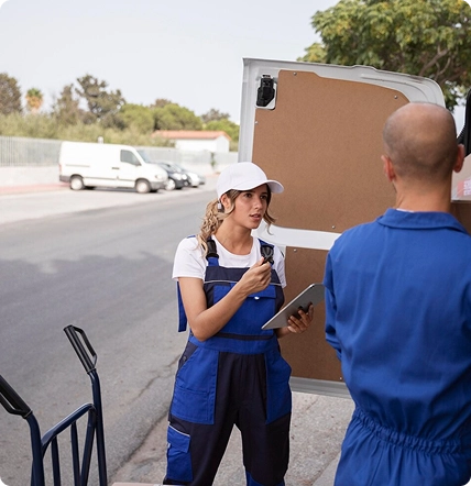 female moving staff checking inventory and talking with coworker beside delivery van